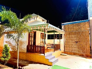 Une maison à deux étages avec un balcon, une clôture en bois et un grand portail en bambou.