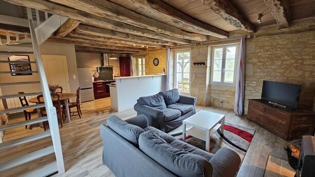 Un salon confortable avec un canapé, un téléviseur et un escalier menant à la cuisine.