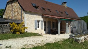 Une maison en pierre avec un toit rouge et une véranda couverte.