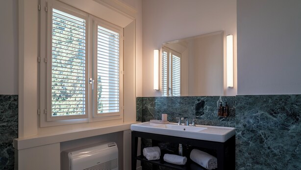 A bathroom with a white sink, a large mirror, and a window with blinds. - Agri Resort Villa Monty Banks (Cesena)