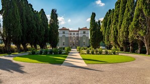 A symmetrical garden with a central pathway leading to a classical building with arched windows and a tiled roof. - Agri Resort Villa Monty Banks (Cesena)