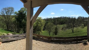 Une pergola en bois offrant une vue sur une colline verdoyante et des arbres.