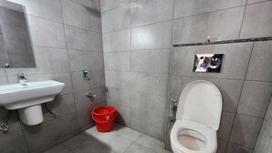 Un baño con un lavamanos blanco, un inodoro y un cubo rojo.