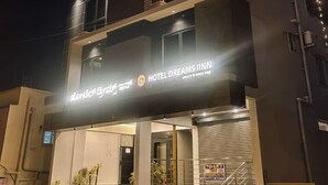Un hotel de varios pisos con un cartel llamativo que dice "HOTEL DREAMS INN", una escalera que conduce a la entrada y un letrero que indica un baño de 93 metros cuadrados.