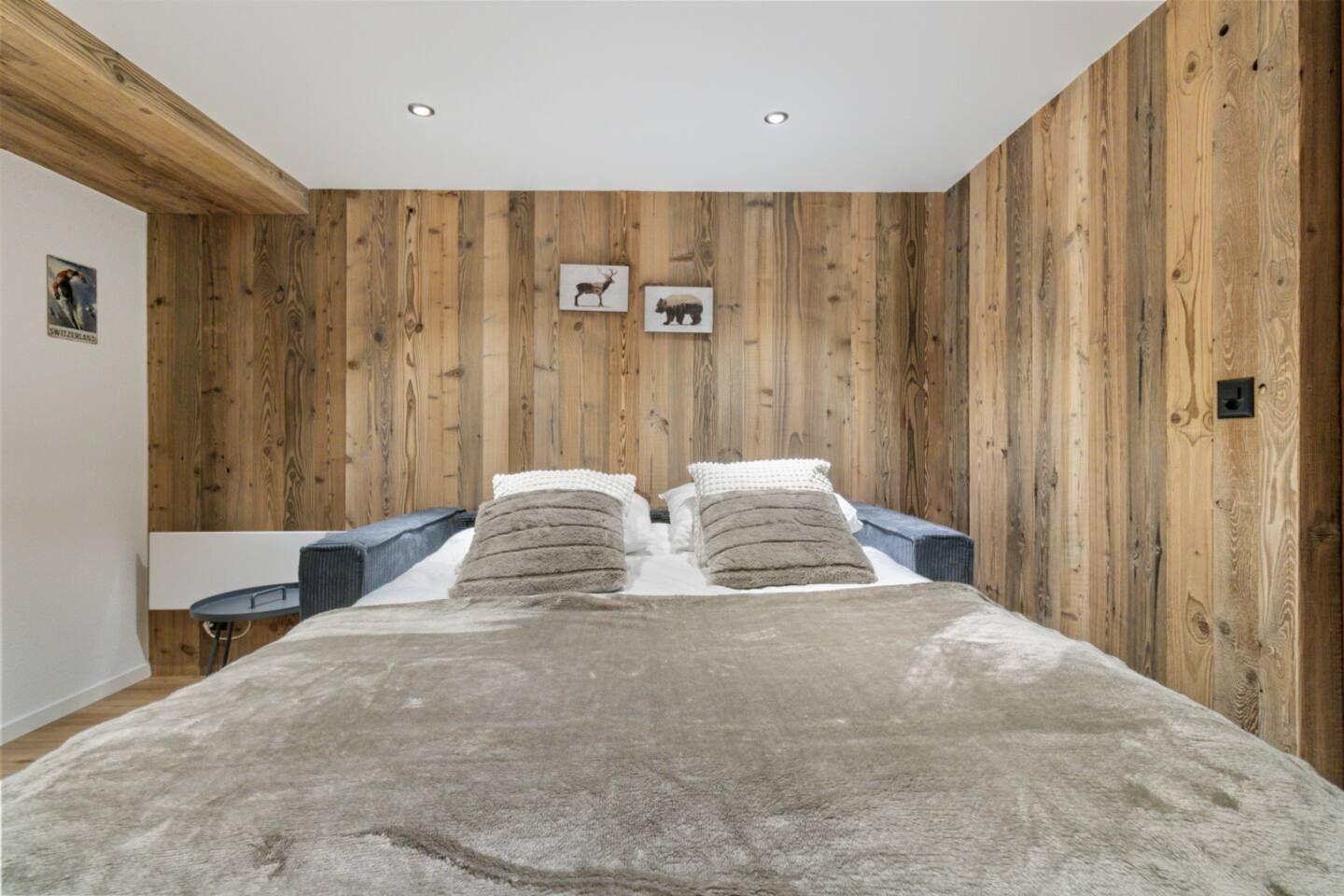 Une chambre avec un mur recouvert de panneaux de bois, un lit avec deux oreillers et une petite table de chevet.