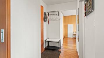 Un pasillo con un banco, un tendedero y una puerta que da a otra habitación.