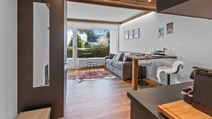 A modern living room with a sofa, a dining table, and a view of the outdoors. - Studio type chalet plein centre (Crans-Montana)