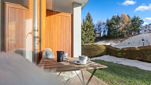A wooden table with a black cup and a white cup on a balcony with a view of a snowy landscape and trees. - Studio type chalet plein centre (Crans-Montana)