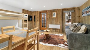 A cozy room with a wooden interior, a sofa, a dining table with chairs, a small round table, and a cowhide rug.