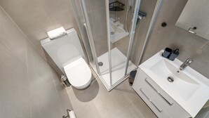 A modern bathroom with a toilet, shower, and sink.