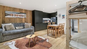 A modern apartment with a grey sofa, wooden dining table, and a cowhide rug.
