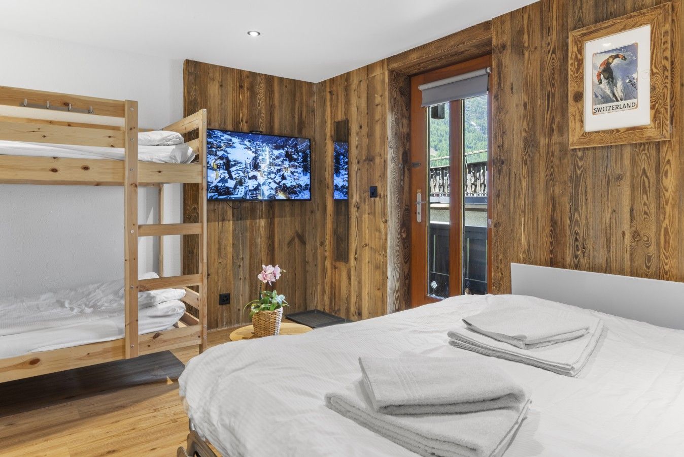 Une chambre avec un lit superposé, une télévision, un tableau encadré et une fenêtre donnant sur un beau paysage.
