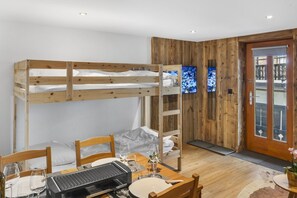 A bunk bed room with a dining table, chairs, and a grill. - Elegant studio in the heart of the Alps (Saas-Fee)