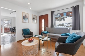A modern living room with a sofa, armchairs, a coffee table, and artwork on the walls.