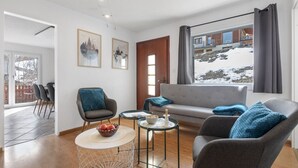 A modern living room with a sofa, armchairs, a coffee table, and artwork on the walls.