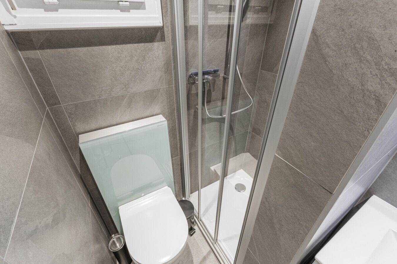 A modern bathroom with a glass shower enclosure, a toilet, and a sink.