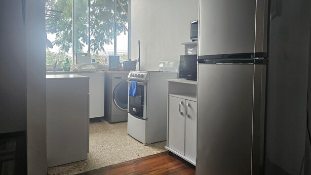 A compact kitchen with a washing machine, a microwave, and a refrigerator.