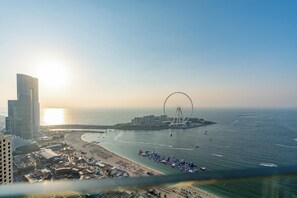Paisagem costeira com um grande roda gigante, praia e edifícios altos.