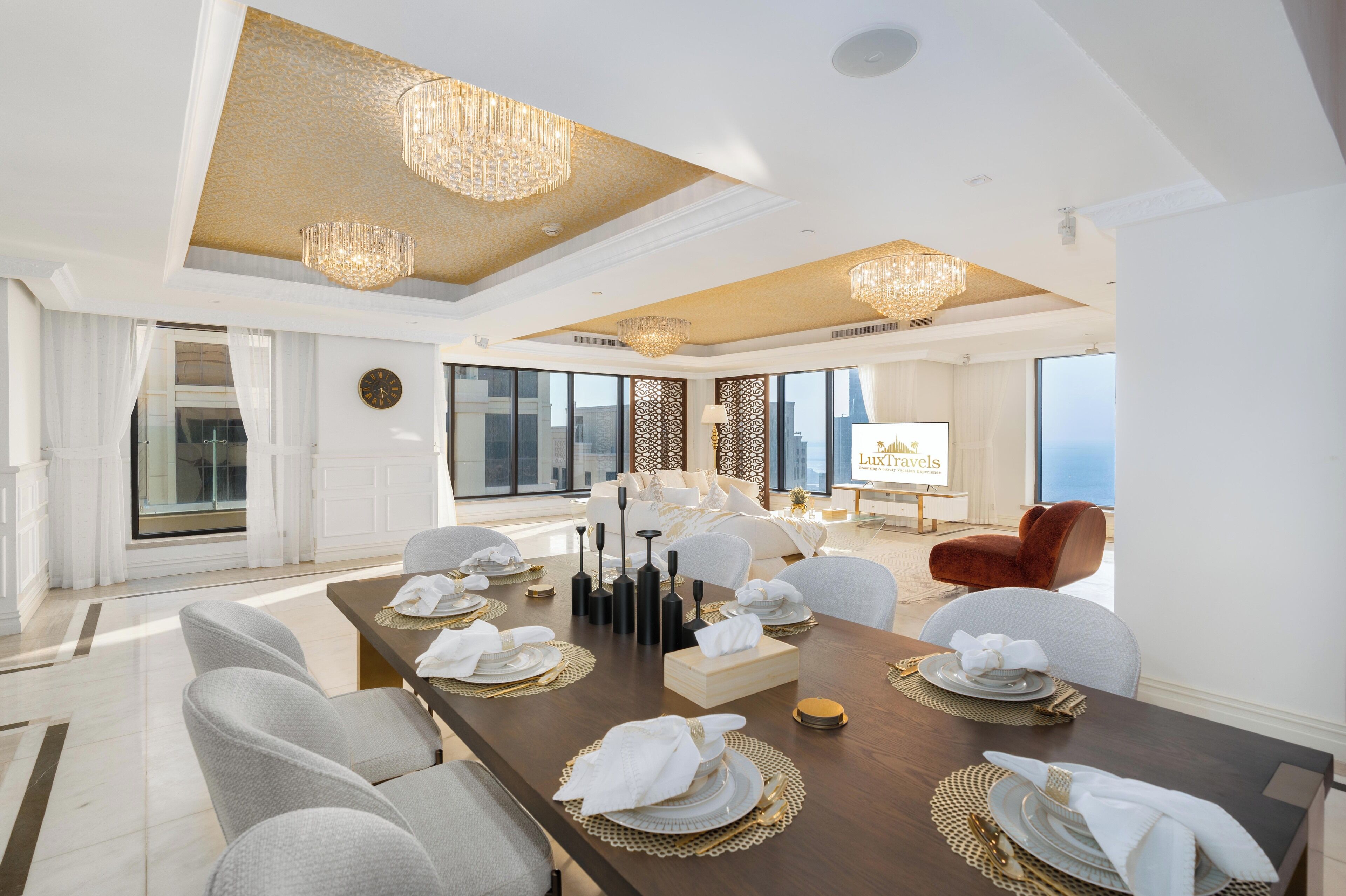 Une vaste salle à manger avec une longue table dressée pour le repas, de magnifiques lustres et une vue sur la ville.