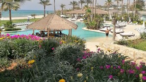 A resort pool area with lounge chairs, a thatched-roof pavilion, and a view of the beach and ocean. - Laguava Resort (Rumayla)