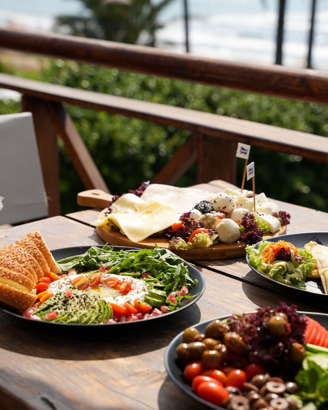 A wooden table with various dishes including salads, bread, and cheese.