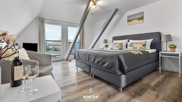 A modern bedroom with a bed, bedside tables, a sofa, and a balcony. - Apartment 24 - 1-room apartment, TV, shower (Kappeln)