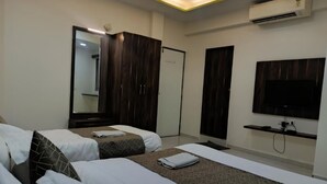 Une chambre d’hôtel avec deux lits, un grand miroir, une armoire, un téléviseur à écran plat et un appareil de climatisation.
