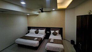 Une chambre d’hôtel avec deux lits, un ventilateur de plafond et un mur décoré de motifs.