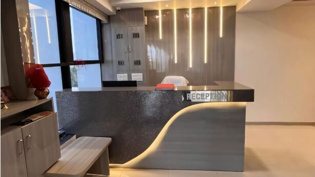 Un comptoir d’accueil moderne au design épuré, un banc et une vue sur l’espace d’accueil.