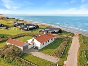 A coastal property with multiple buildings, a paved driveway, and a beach view.