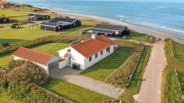Um imóvel costeiro com vários edifícios, um caminho para a praia e vista para o mar.