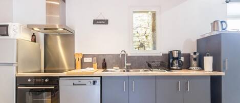 A modern kitchen with stainless steel appliances, grey cabinets, and a wooden ceiling.