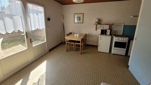 A small kitchen with a dining table, a microwave, a stove, and a refrigerator.