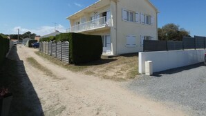 Ein zweistöckiges Haus mit Balkon, Kiesauffahrt und einem Metallzaun.