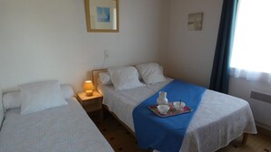 Ein Hotelzimmer mit zwei Betten, einem Nachttisch mit Lampe, einem Tablett mit Tassen und einer Vase sowie einem gerahmten Bild an der Wand.