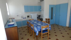 Een kleine keuken met blauwe kastjes, een magnetron, een fornuis en een spoelbak.