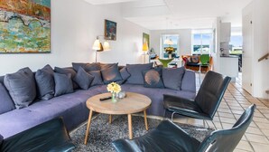 A modern living room with a sectional sofa, a round coffee table, and a view of the dining area. - Modern Beach House - By Traum Ferienwohnungen (Lokken)