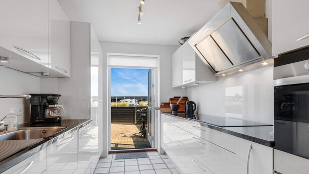 A modern kitchen with white cabinetry, a coffee machine, and a view to the outside. - Modern Beach House - By Traum Ferienwohnungen (Lokken)