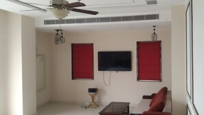 A room with a ceiling fan, a mounted TV, and a red-framed window. - Hotel Chandraa Celebration (Dehradun)