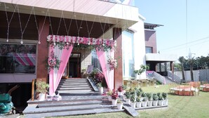 A building with a covered entrance, steps leading up to it, and outdoor seating area. - Hotel Chandraa Celebration (Dehradun)