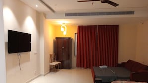 A hotel room with a bed, a TV mounted on the wall, a wardrobe, and a ceiling fan. - Hotel Chandraa Celebration (Dehradun)
