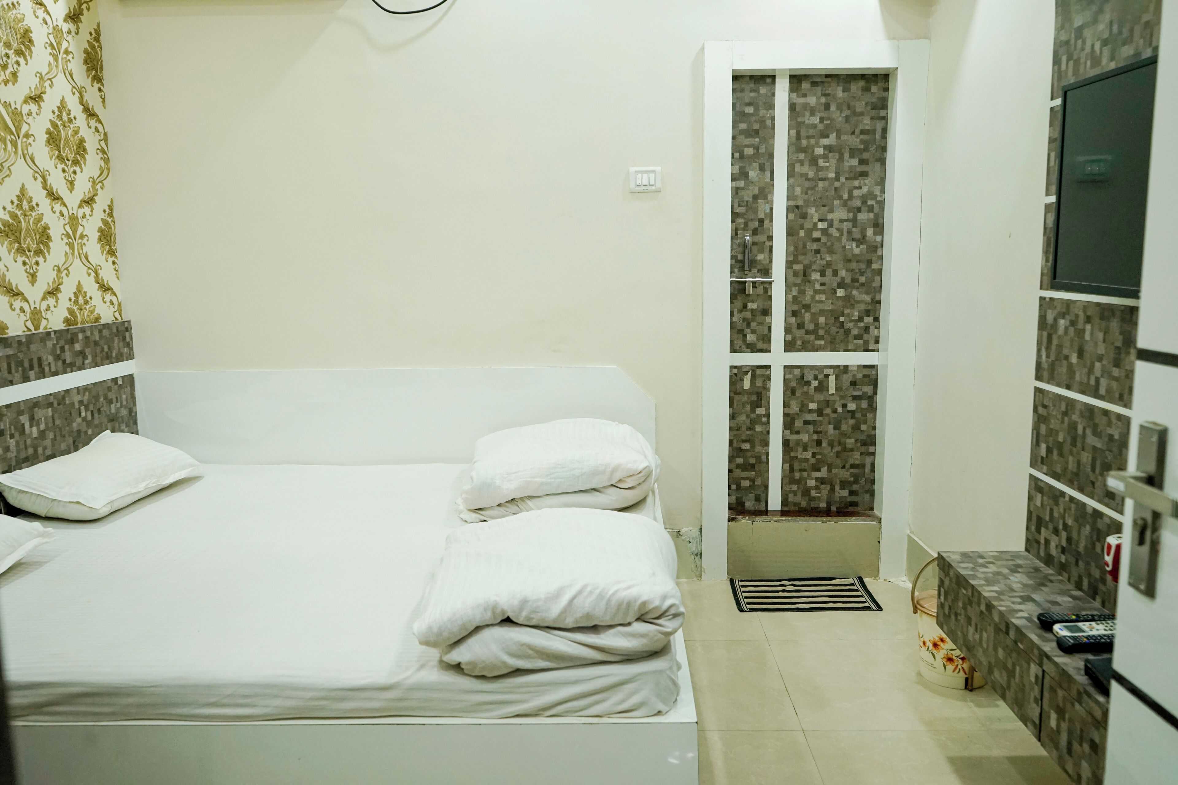 Un dormitorio con cama, un baño pequeño con ducha y una zona de kitchenette.