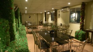 A dining area with multiple tables and chairs, air conditioning units, and a window with a view. - KUMAR HILIFE (Kendujhar)