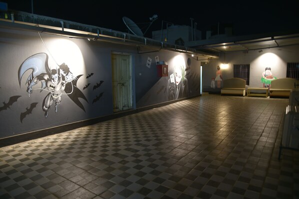A hallway with a checkered floor, a wall with a mural, and a door.
