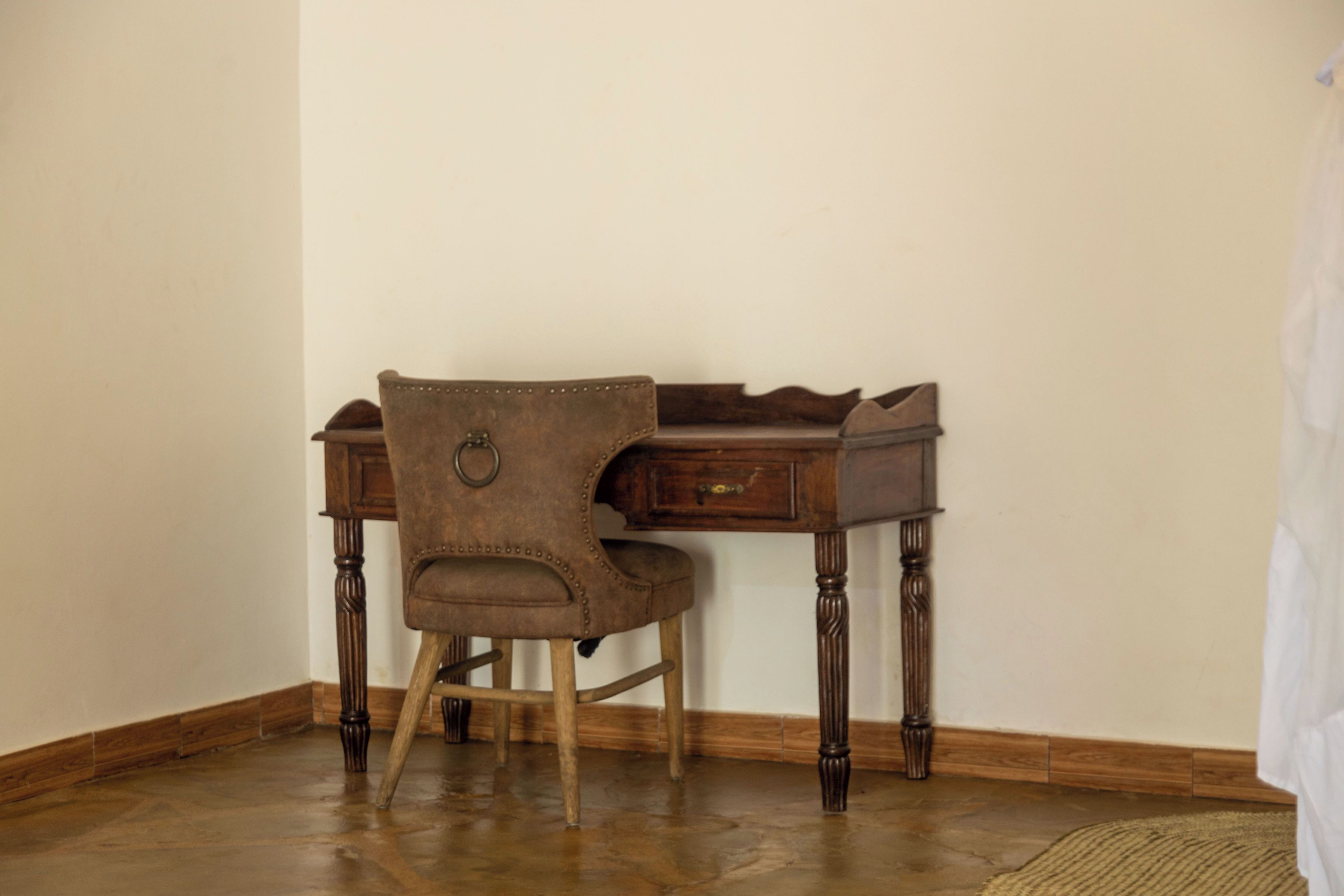 Un escritorio en esquina con una silla de cuero y una mesa de madera.
