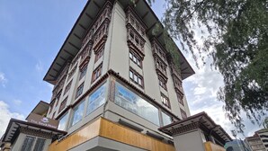 A multi-story hotel with a traditional architectural style, featuring a prominent entrance with a wooden facade and stone pillars. - The Seva Hotel (Thimphu)