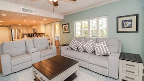 A living room with a grey sofa, a wooden coffee table, and a small white side table.