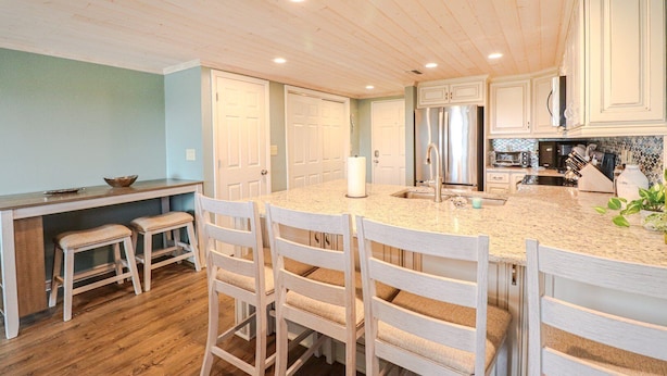 A kitchen with wooden cabinets, a granite countertop, and a stainless steel refrigerator.