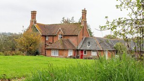 A traditional brick house with two chimneys, a red door, and a well-maintained lawn. - Tranquil Forest Retreat in Brockenhurst (Brockenhurst)