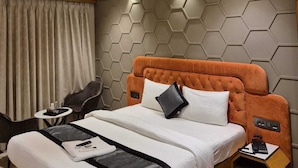 A modern hotel room with a large bed, a desk, and a ceiling fan. - Hotel Regalia Suites (Navi Mumbai)